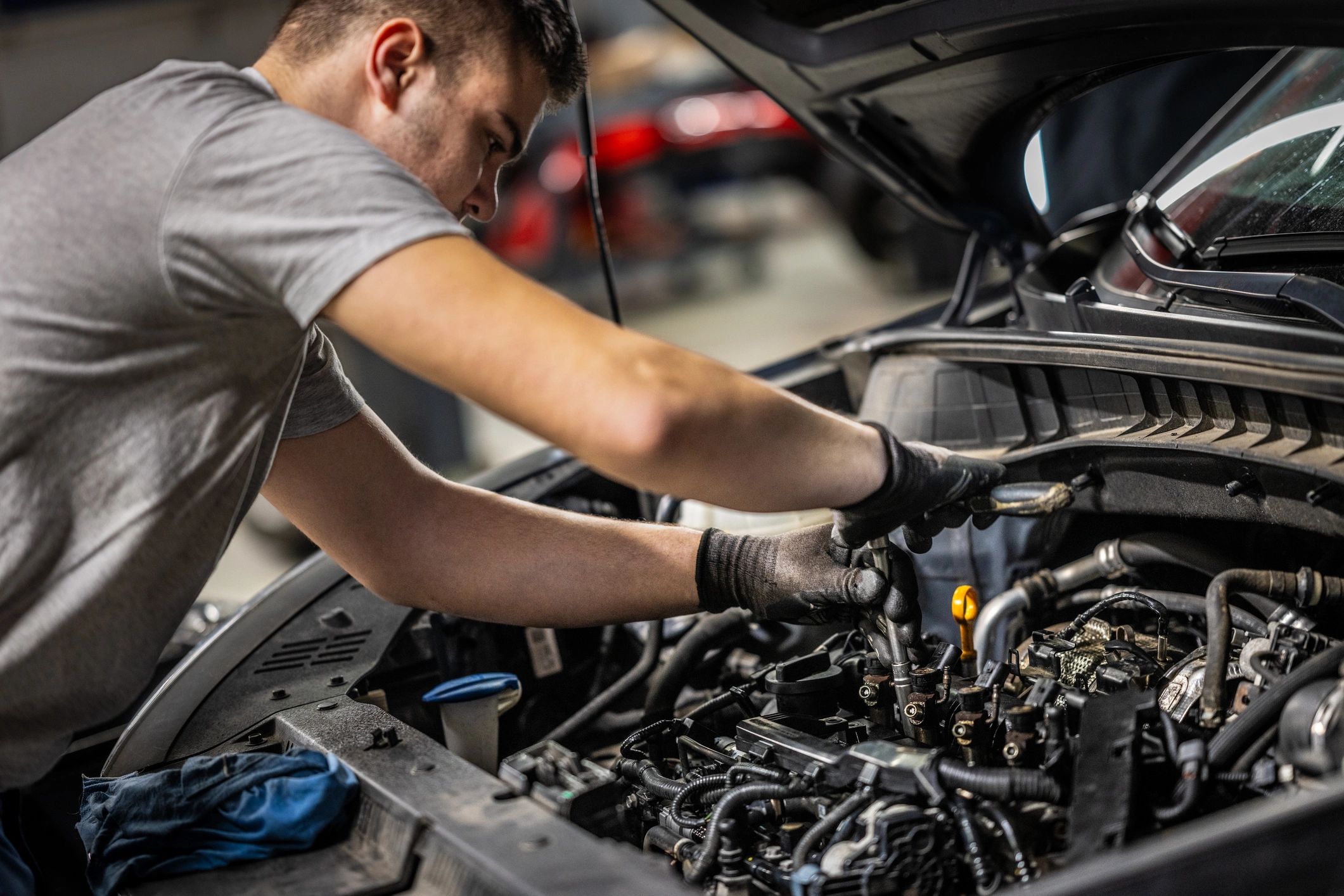 Mechanic performing detailed maintenance under the hood in an auto workshop